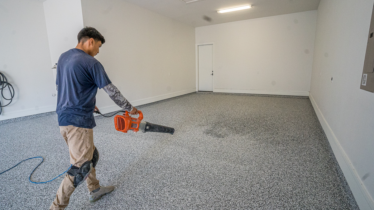 Blowing flakes to spread on concrete floors before second garage coating applied