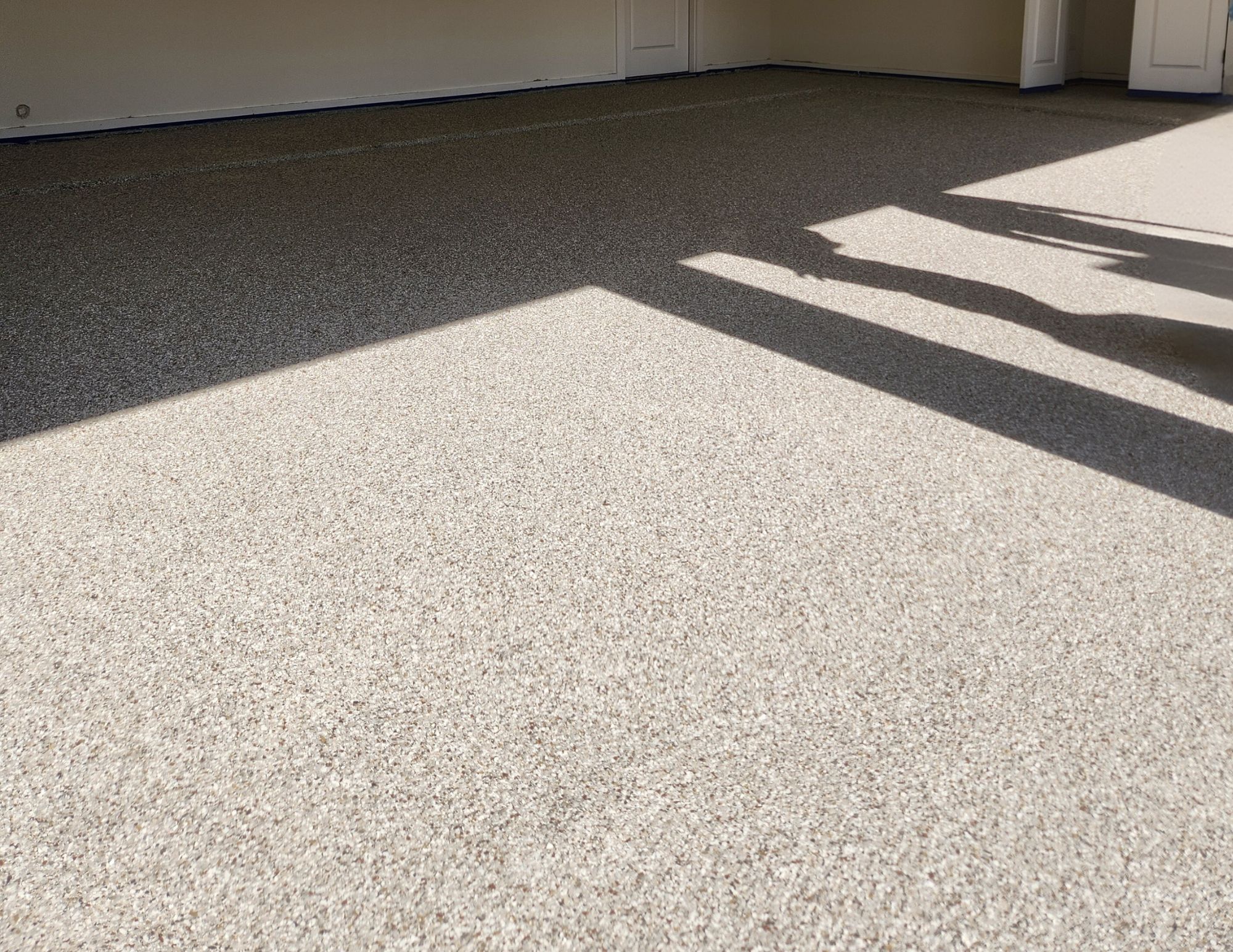 a Close-up of a Garage Floor with a Fresh Polyaspartic Coating, Showcasing a Seamless and Resilient Surface. - Finished Polyaspartic Floor Coating
