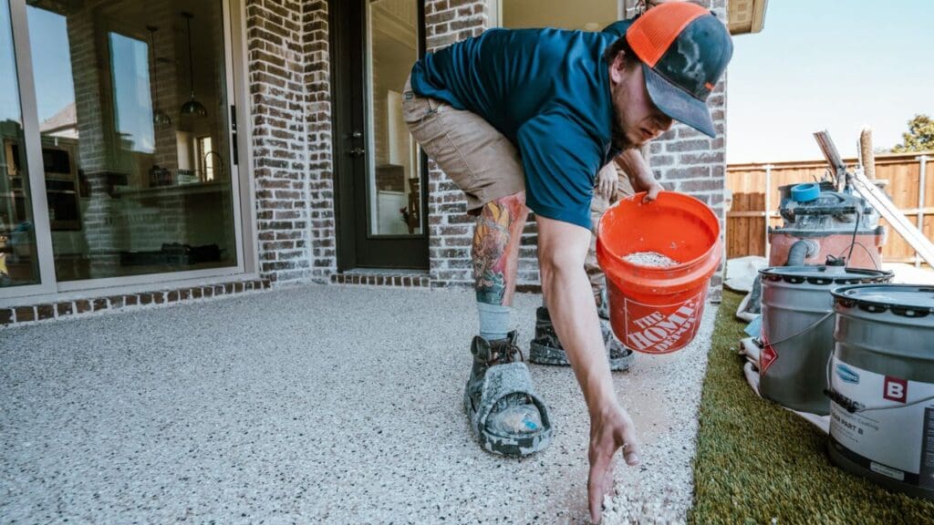 An installer applying the clear polyaspartic top coat to a patio floor with a squeegee