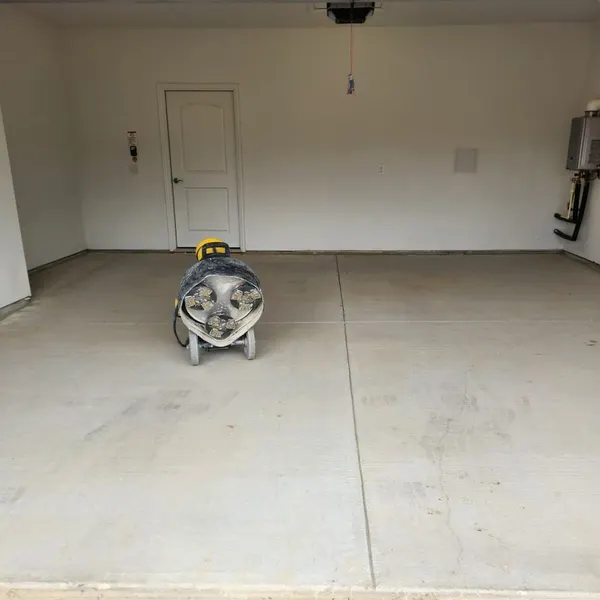 Plain concrete garage floor before coating, with an air mover drying the slab
