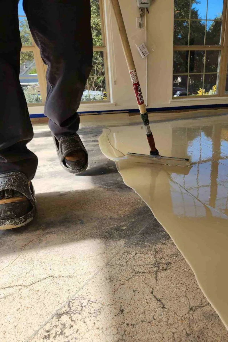 Base coat going down over cracked concrete, spread with a squeegee