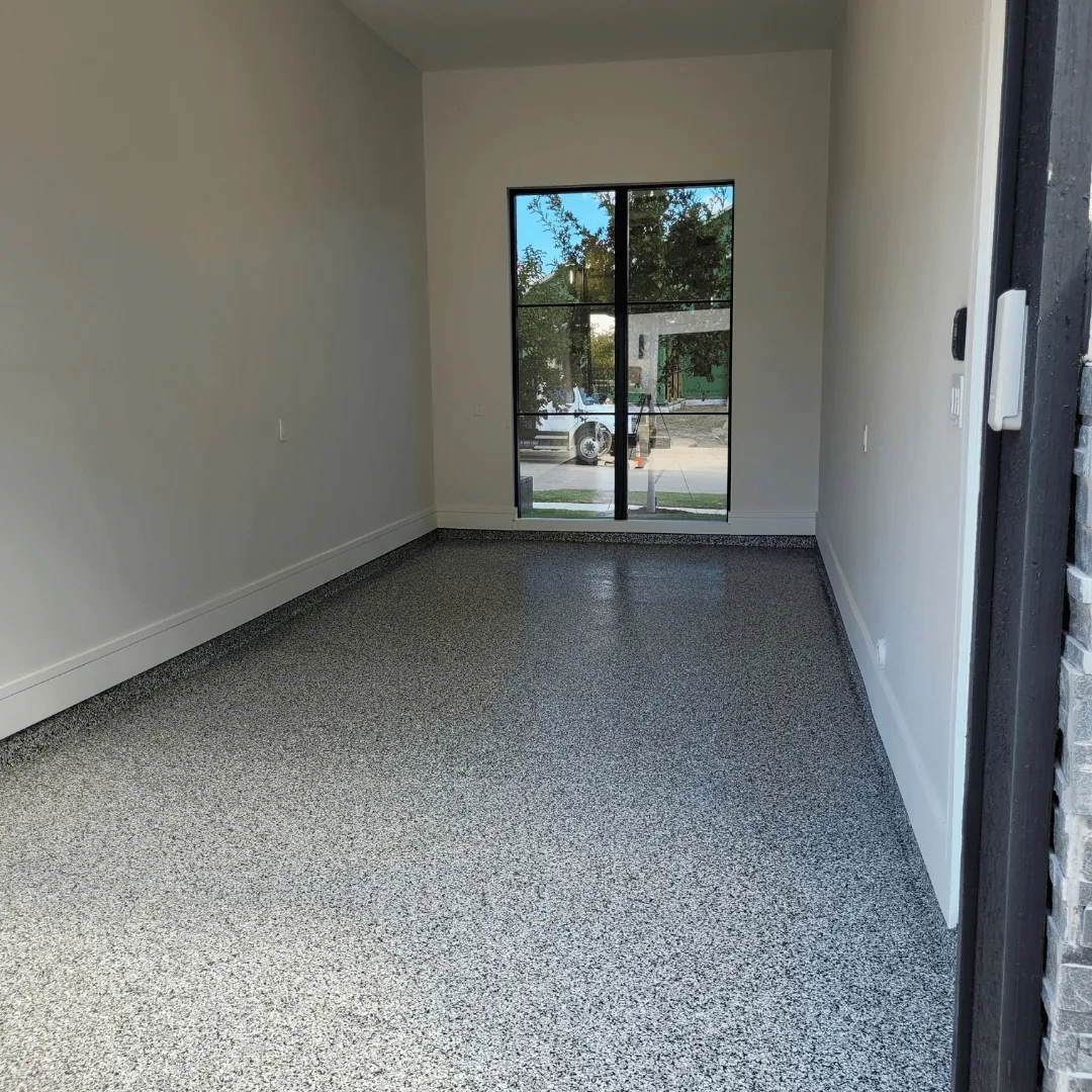 A gray flake floor running the length of a finished garage with a glass door