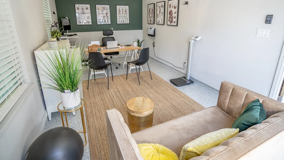 A garage converted into a home office with a desk, chairs and a sofa