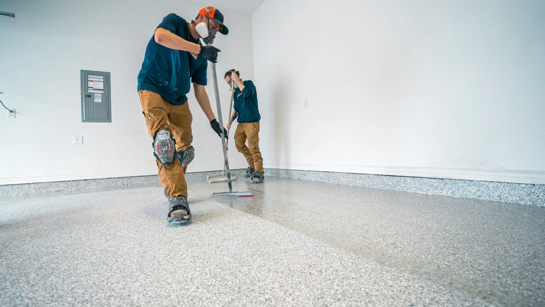 Two MyGarageFloors installers spreading coating across a garage floor