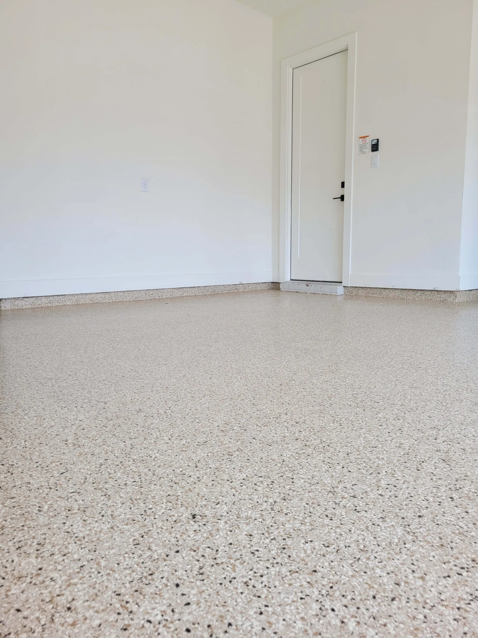 A tan flake floor in a finished garage with white walls