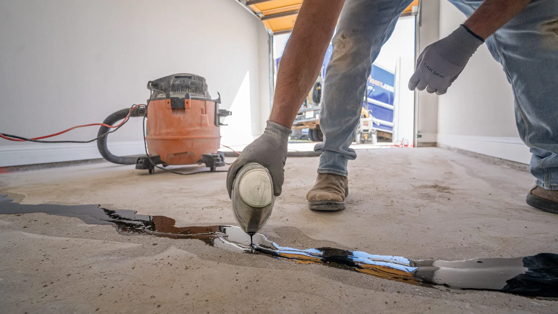 An installer filling a crack in a concrete garage floor before the coating goes down