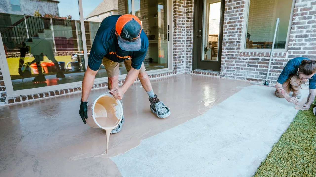 Installers applying a floor coating to a back patio outside a brick house