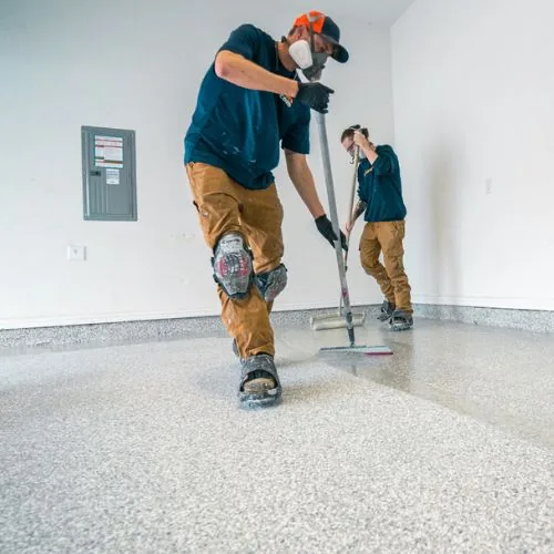 Two MyGarageFloors installers applying a coating to a garage floor
