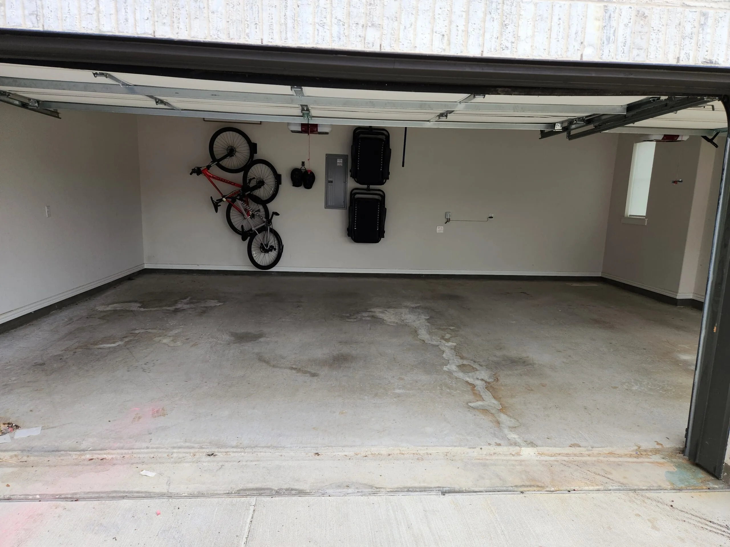 A bare concrete garage floor with discolored patches, before cleaning and coating